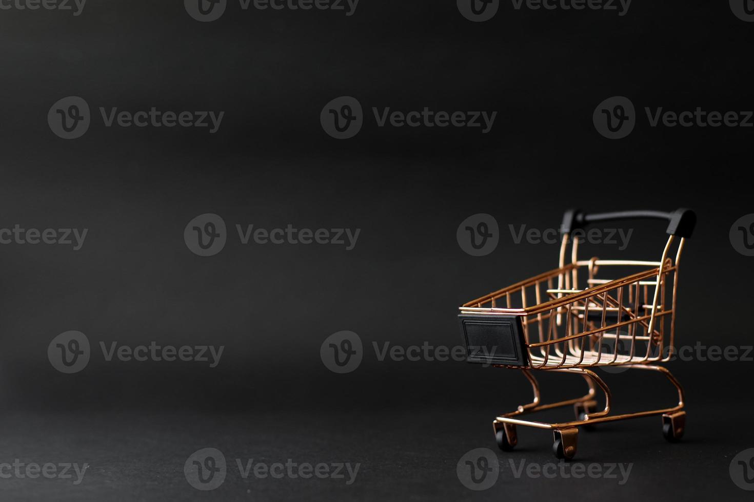 Miniature shopping chart or trolley isolated on black background with copy space photo