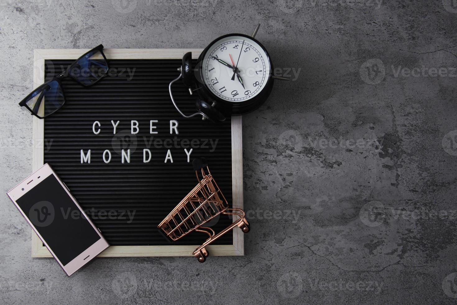 Creative flat lay promotion composition Cyber Monday sale text on letter board with alarm clock goodie bag and gadget photo