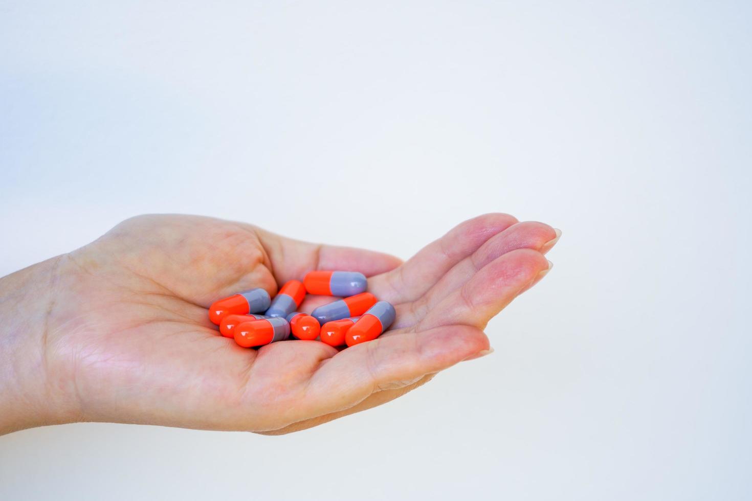 Female hand holding capsule tablet or medication pill on white background photo