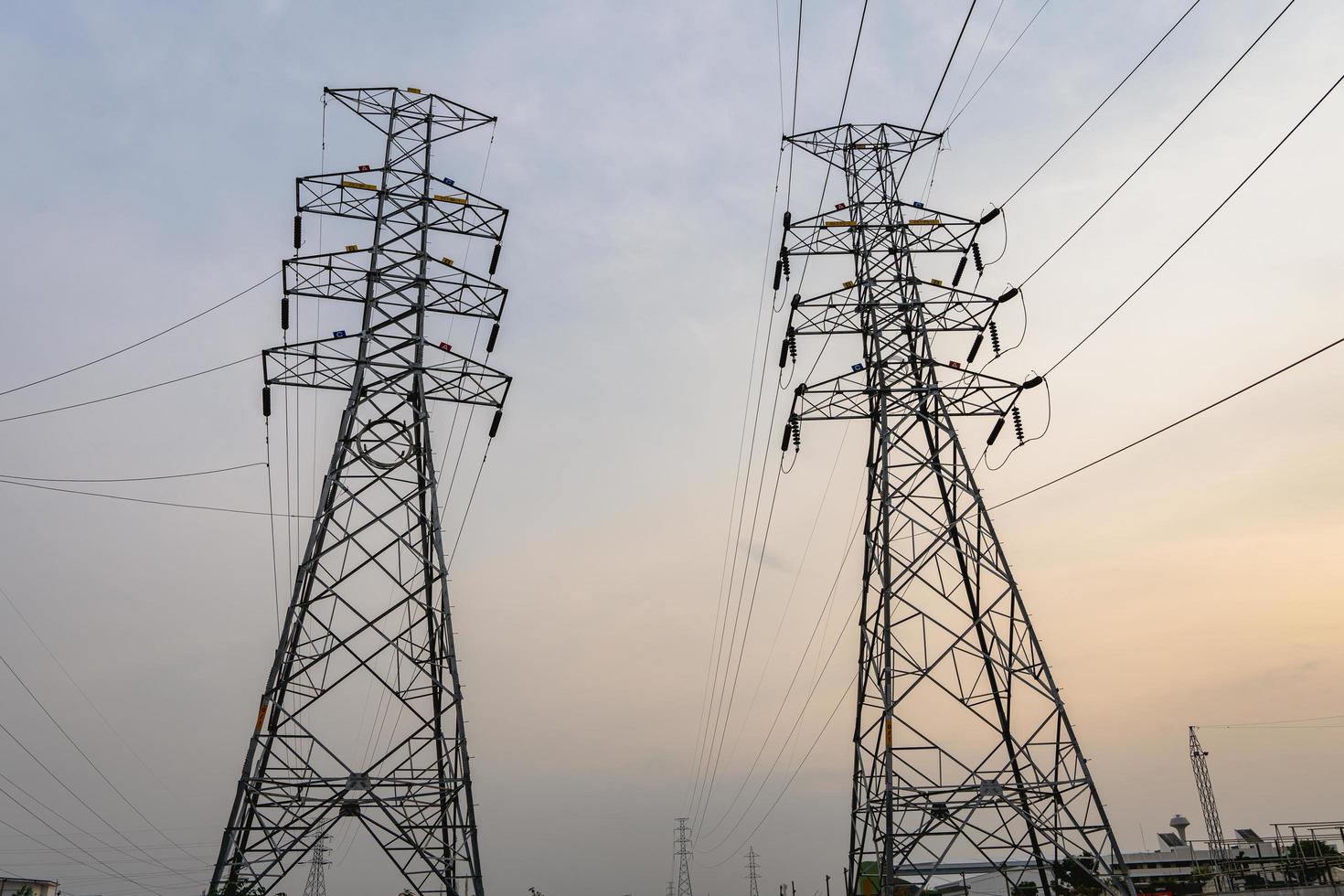 Photo of high-voltage steel poles at a power plant in the evening with the setting sun