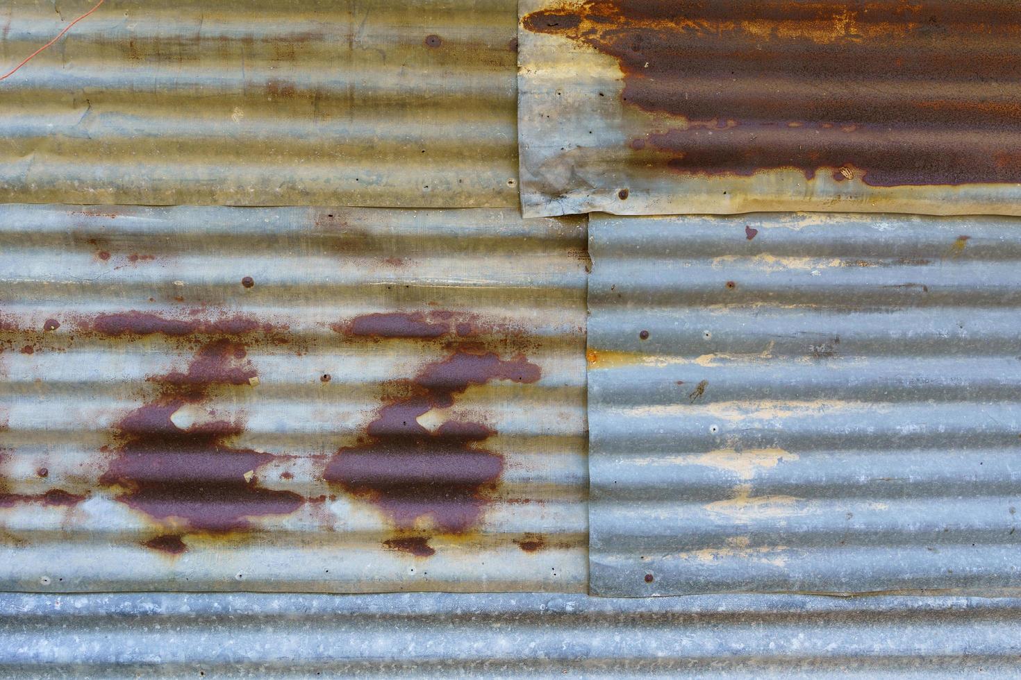 Rusted old galvanized roofing sheets used to make walls of houses of poor rural people photo