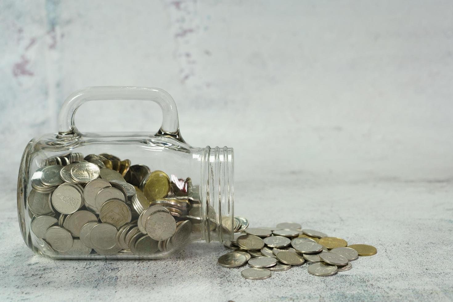 A glass jar with coins poured on the floor. photo