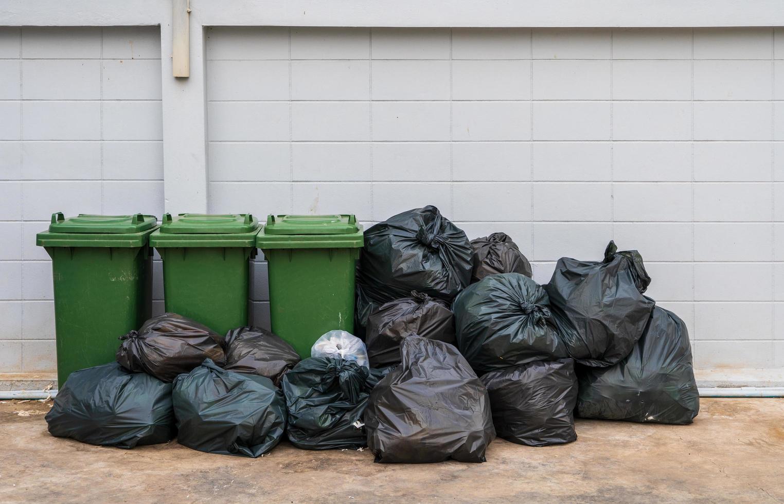 la basura en bolsas negras se coloca con contenedores de basura para separarlos en el sistema de gestión de residuos foto