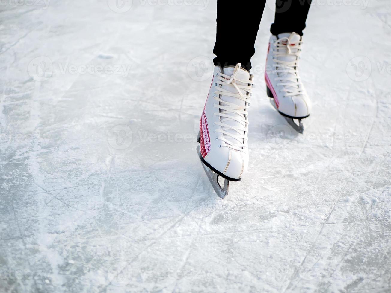 mujer patinando y entrenando con patines blancos en el área de hielo en el día de invierno. fines de semana actividades al aire libre en climas fríos. foto