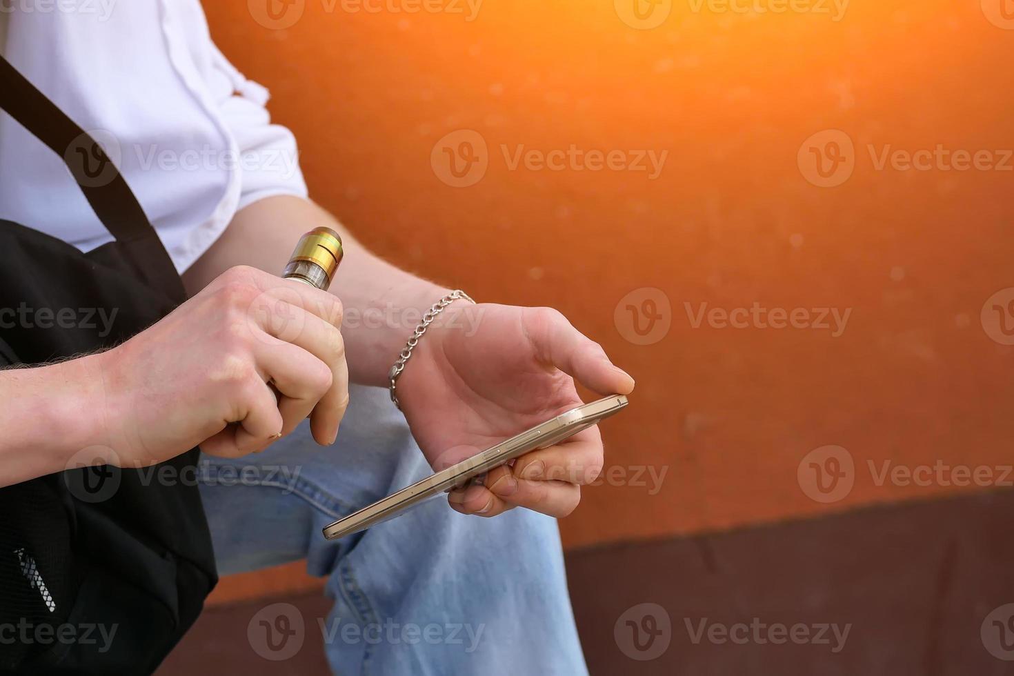 man soars electronic cigarette while sitting with the phone close-up photo