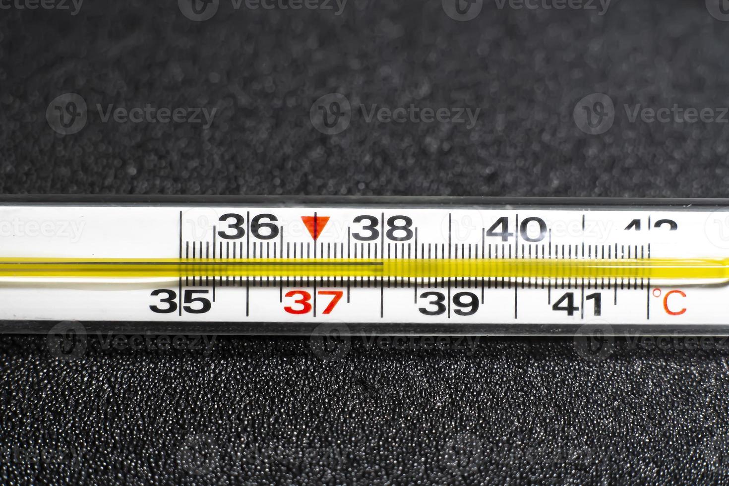 Mercury thermometer  on black background. Close up photo. Thermometer shows a temperature of 38 degrees Celsius photo