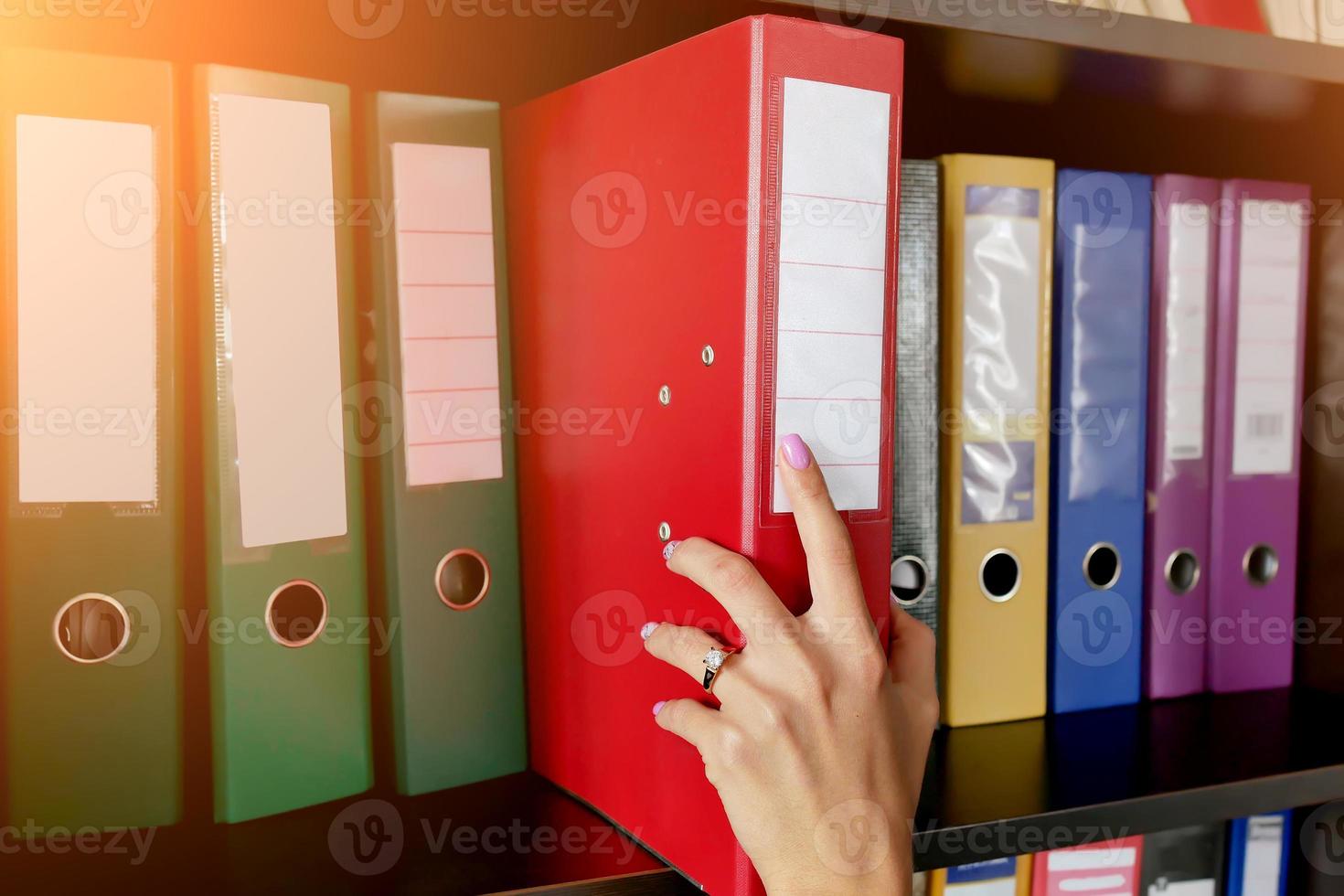 the girl in the archive puts a folder with documents on the shelf close-up photo