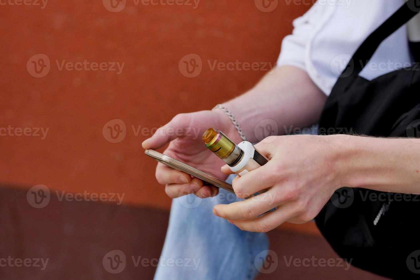 a man sits with a phone and vaping photo