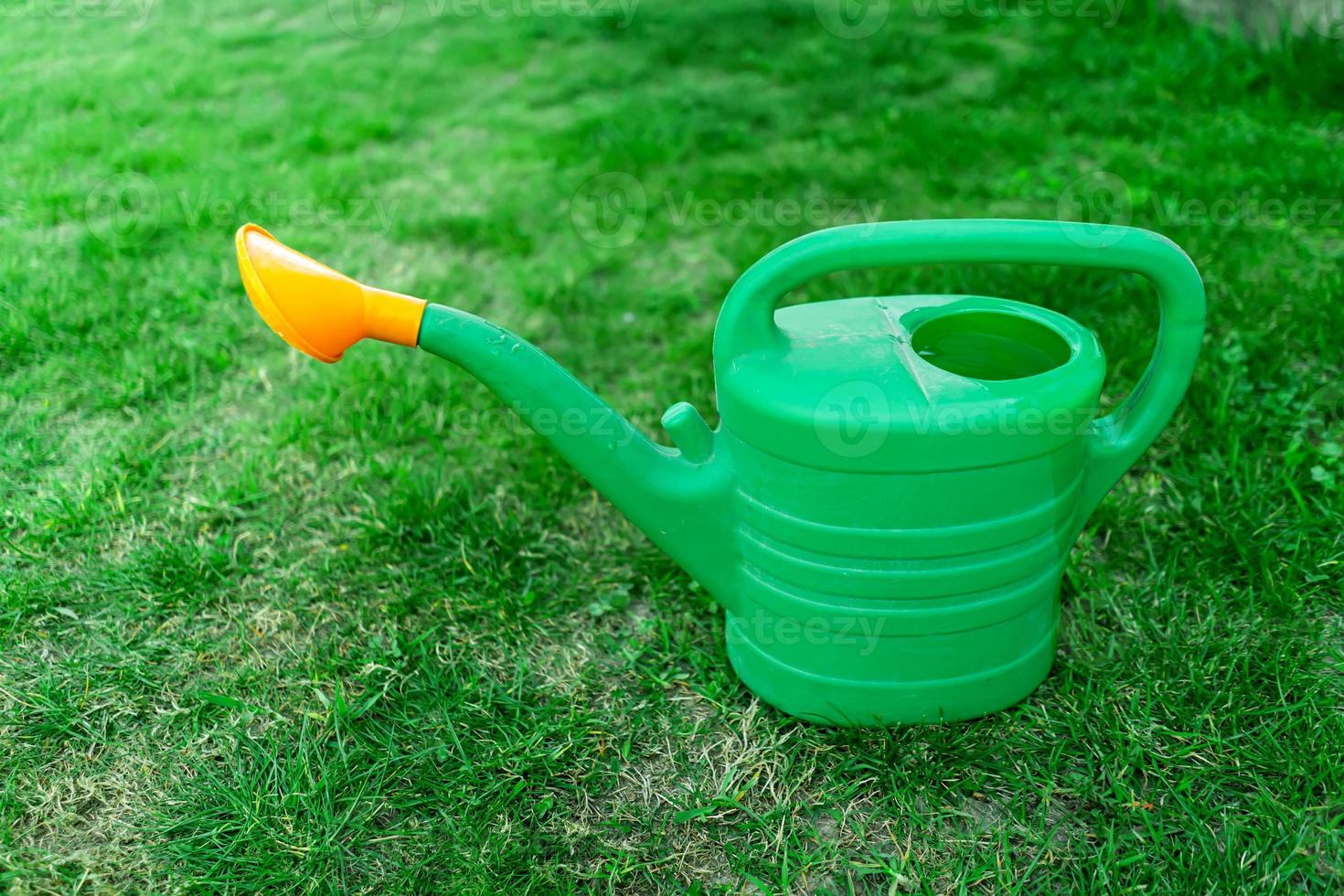 green watering can on the lawn photo