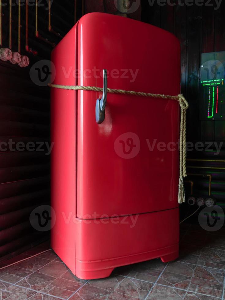 red vintage refrigerator tied with rope. photo