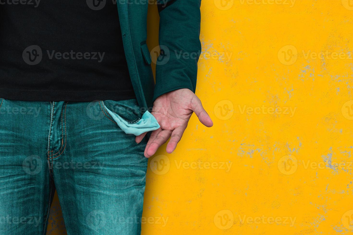 Man showing his empty pocket on yellow wall background. photo