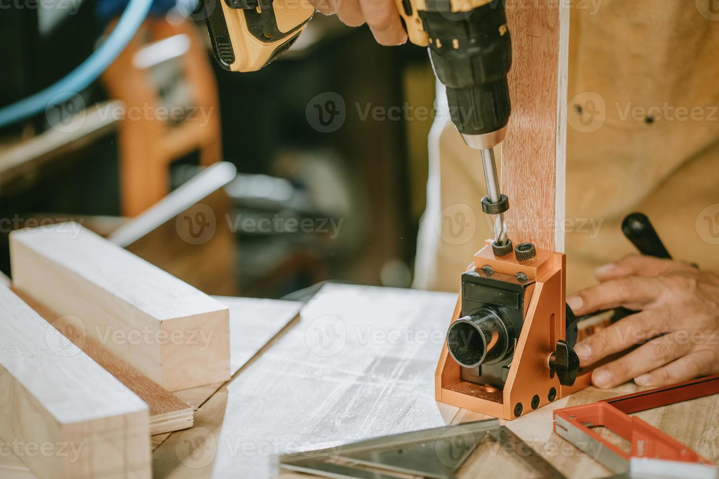 Carpenter use Cordless Drill and pocket hole jig or dowel jig ,Drive the screw on wooden plate,DIY maker and woodworking concept. selective focus photo