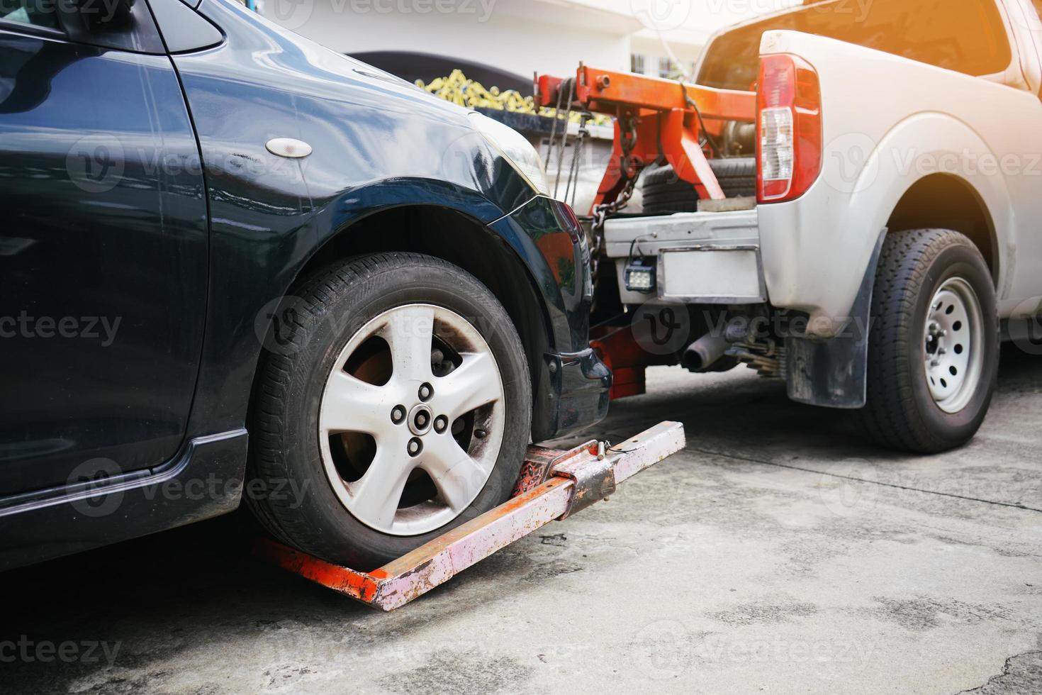 Tow truck picking up and towing old broken down car on a roadside photo