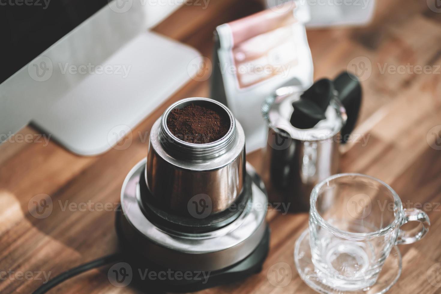 Finely ground coffee and vintage coffee maker moka pot on wooden table at home office photo