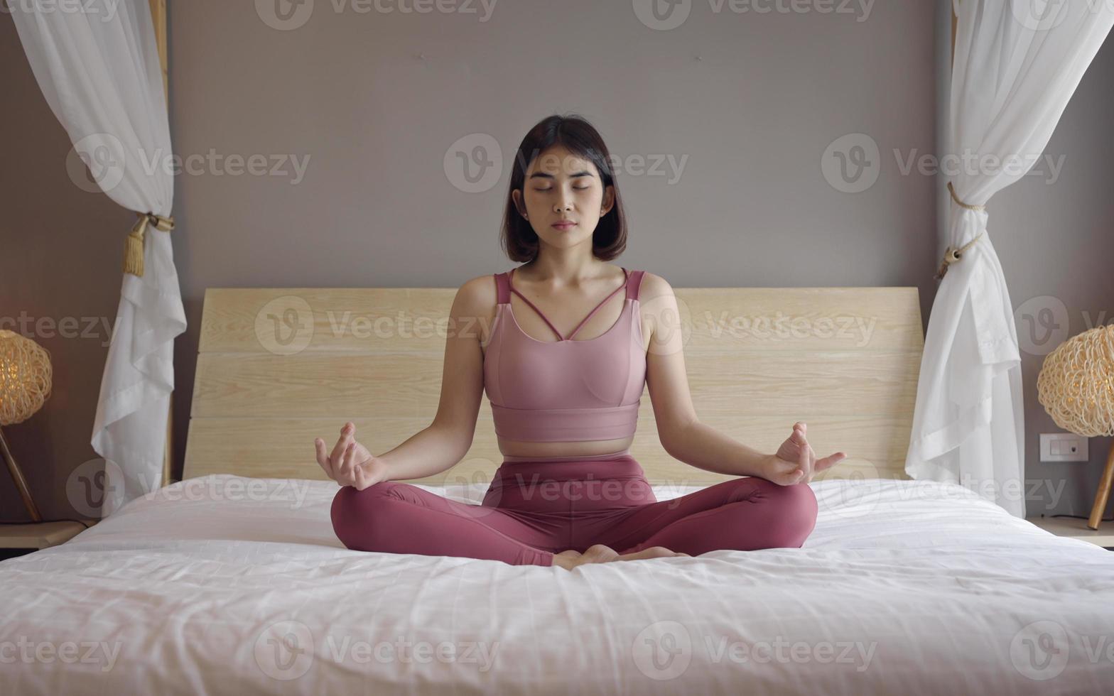 mujer en sportsware practica yoga lotus pose para meditar en casa, mujer de bienestar haciendo yoga para respirar y meditar cómoda y relajada. foto
