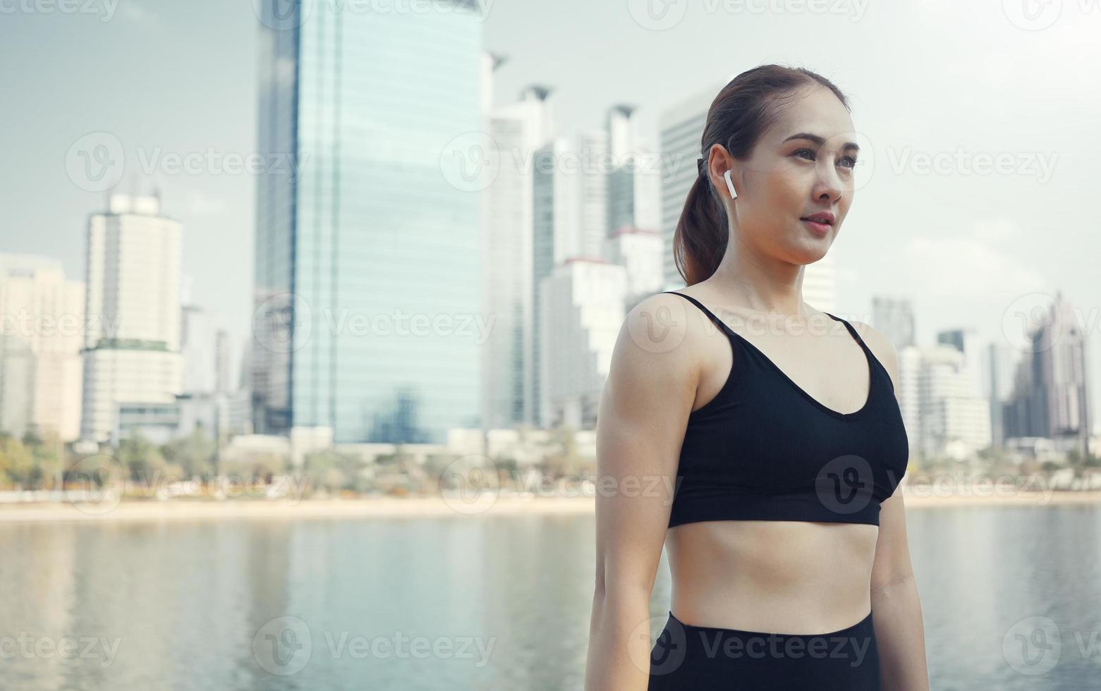 mujer deportiva usando auriculares inalámbricos y estirando los músculos antes de correr en la ciudad, ejercicio de calentamiento. foto