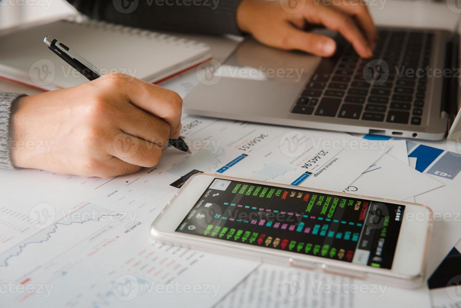 Businesswoman analyze business report graph and finance chart using smartphone and computer laptop at corporate office. photo