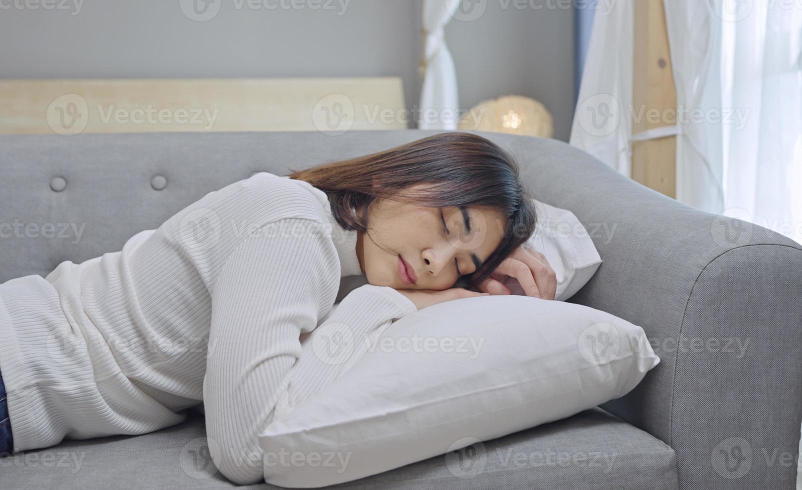 una joven mujer cansada o aburrida se cae sola en el sofá de casa. foto