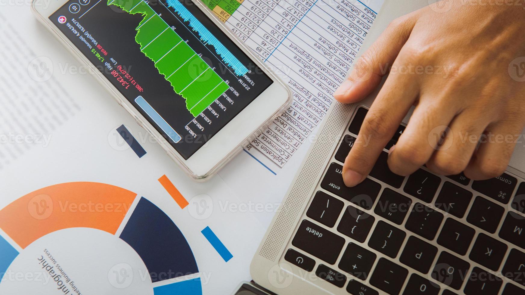 Businesswoman analyze business report graph and finance chart using smartphone and computer laptop at corporate office. photo