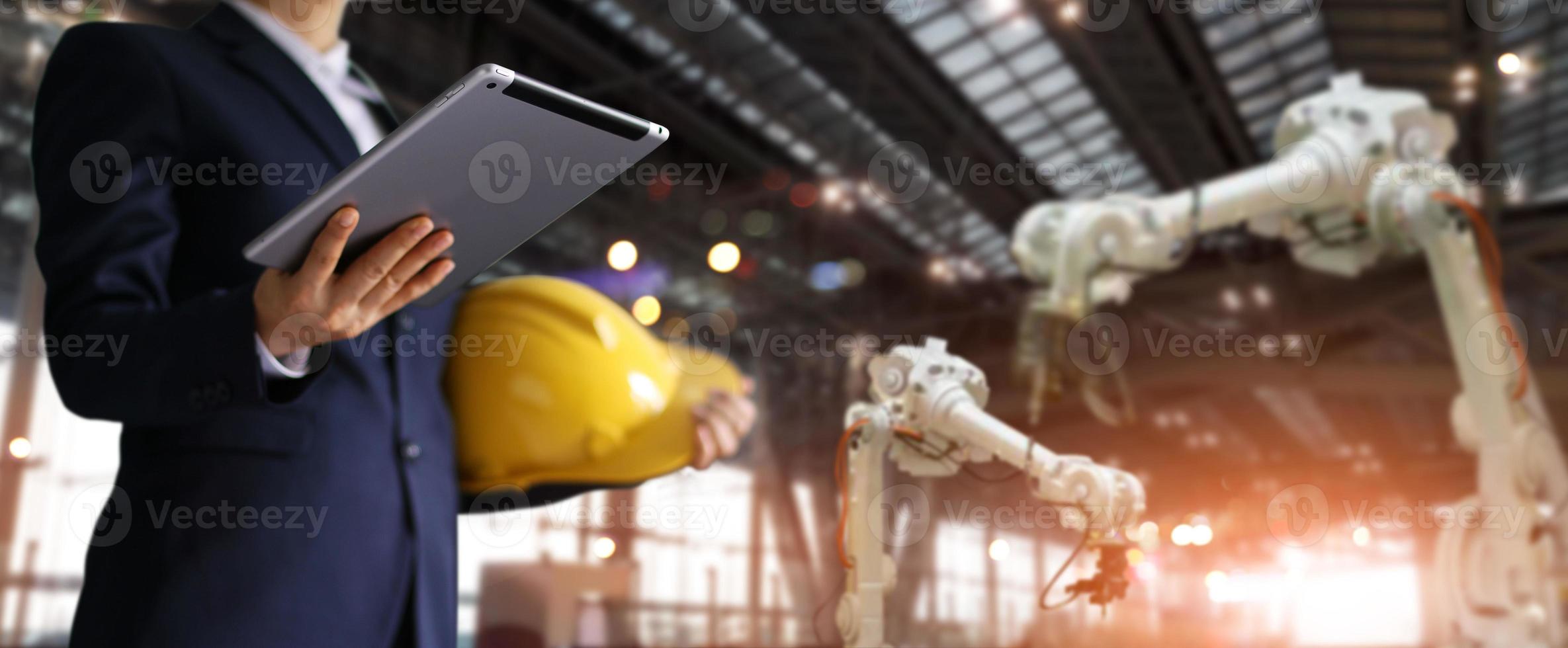 Businessman, Engineer in modern industrial site, using tablet control robot arms. photo