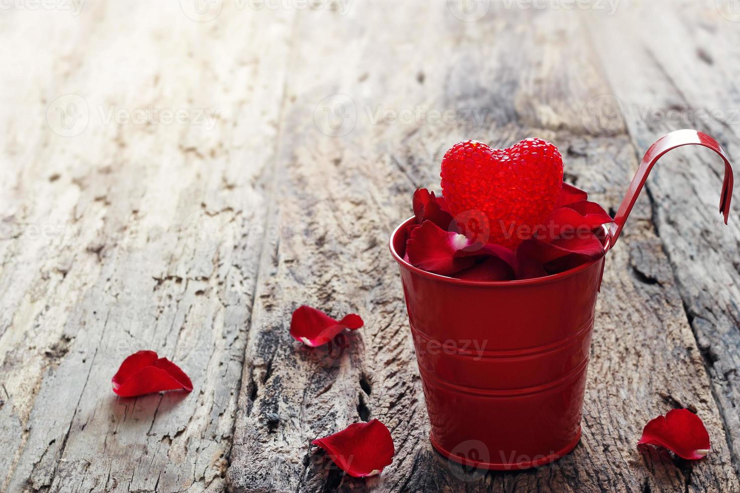 fondo del día de san valentín con corazón en la olla roja llena de pétalos foto