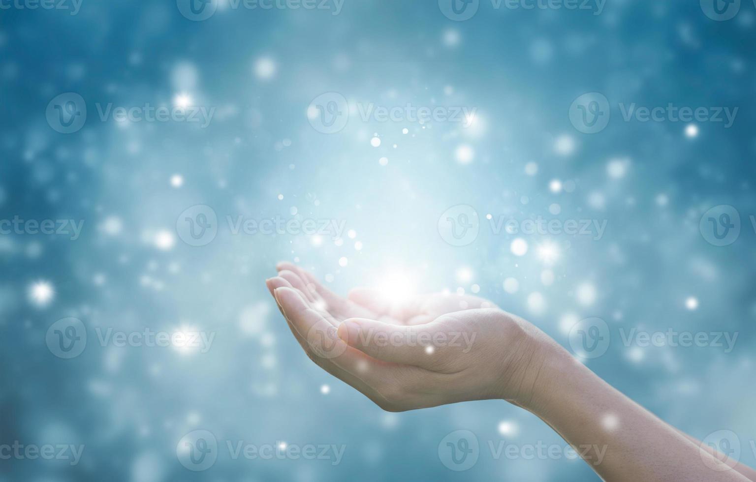 manos de una mujer respetando y rezando sobre fondo de partículas azules foto