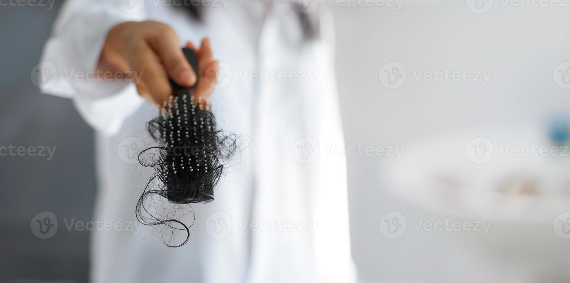 woman losing hair on hairbrush in hand, soft focus photo