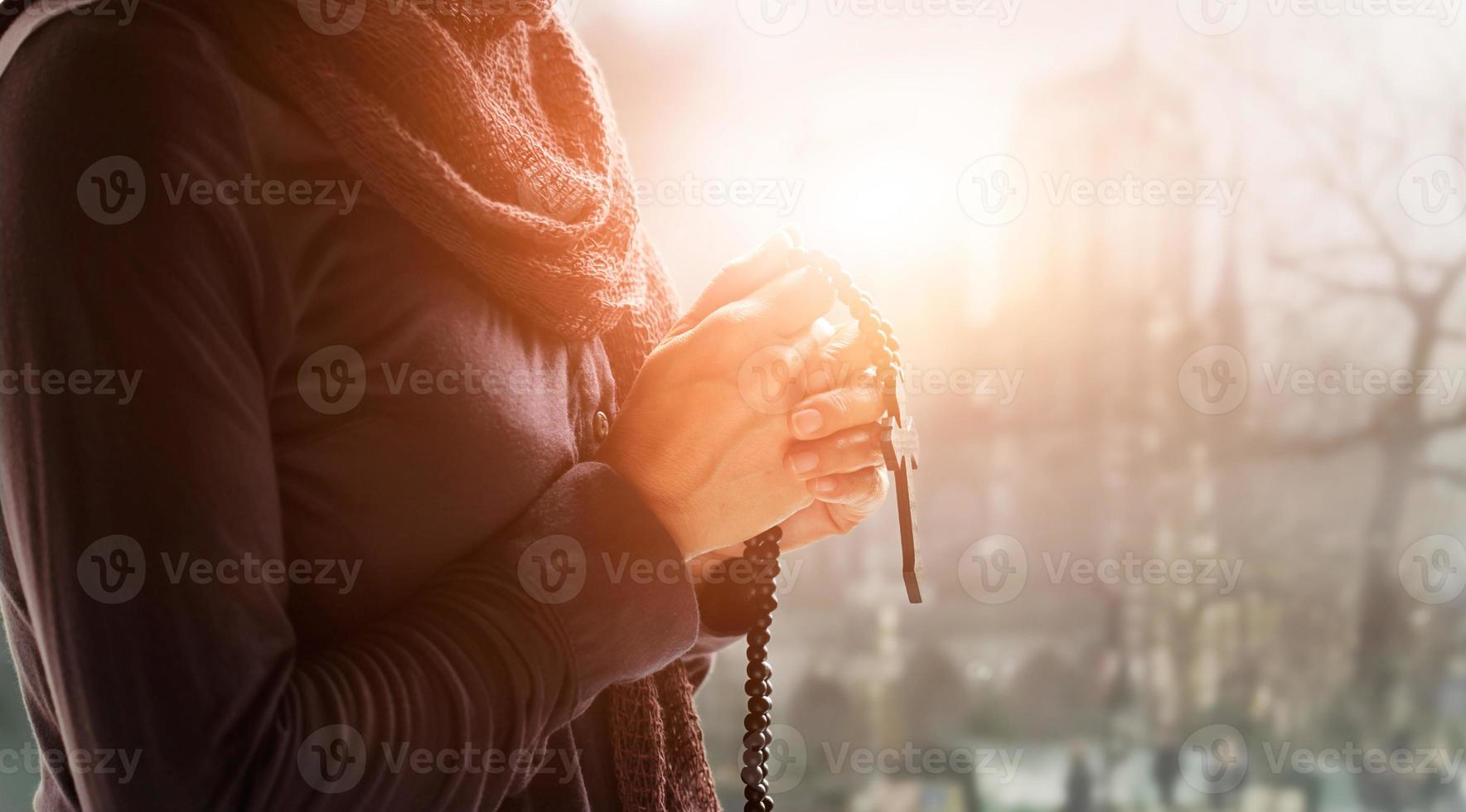 religión cristiana y concepto de esperanza. manos de mujer rezando con rosario y cruz de madera. bendiga a dios ayudando a los católicos en el fondo de la iglesia. foto