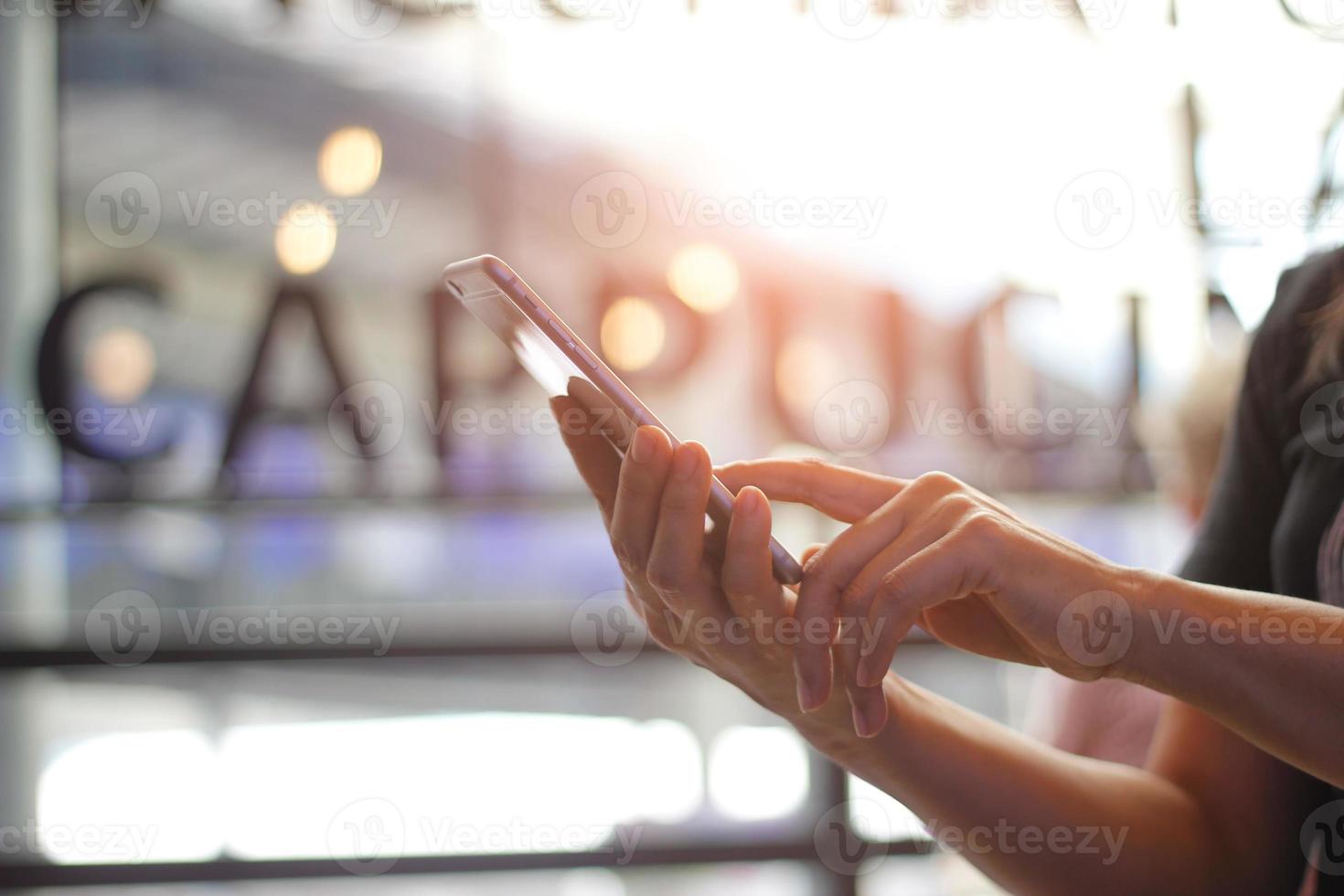 Close up of women's hands holding smarthone. Her watching sms, message, e-mail  on mobile phone in coffee shop. Blurred background. photo