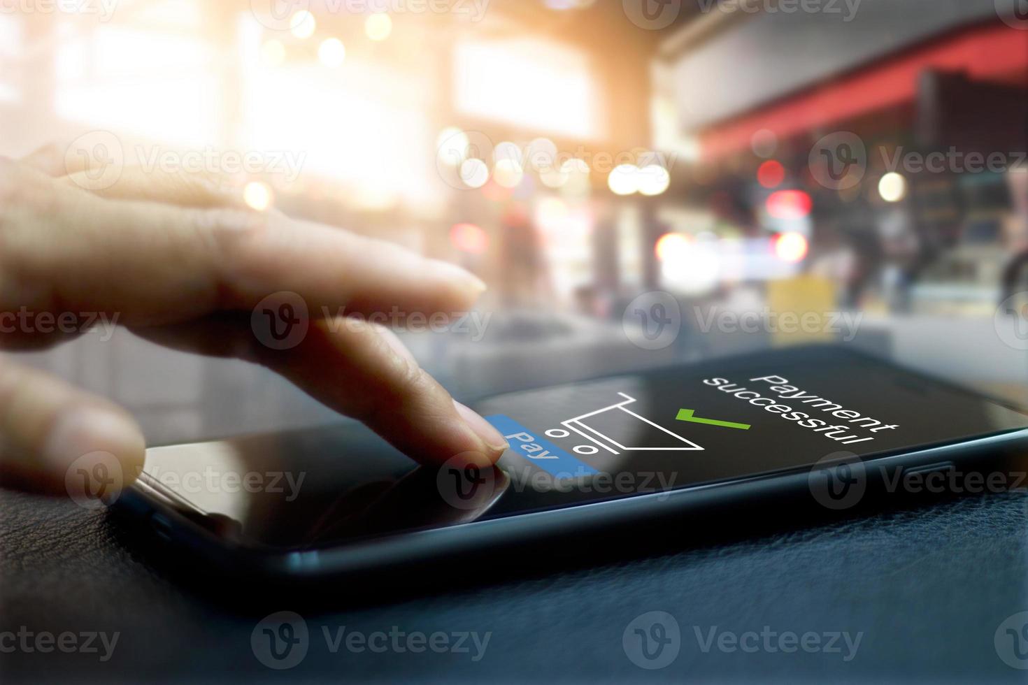 Hand touching mobile screen of a Payment successful message on shopping mall background photo