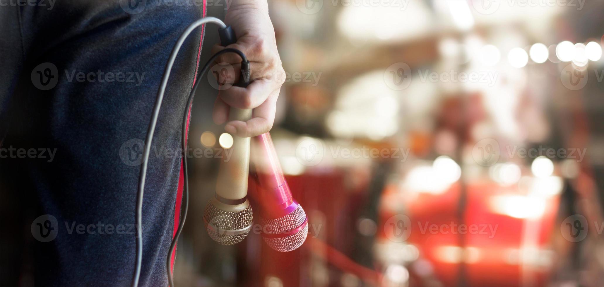 Man holding microphones in hand on concert stage background photo