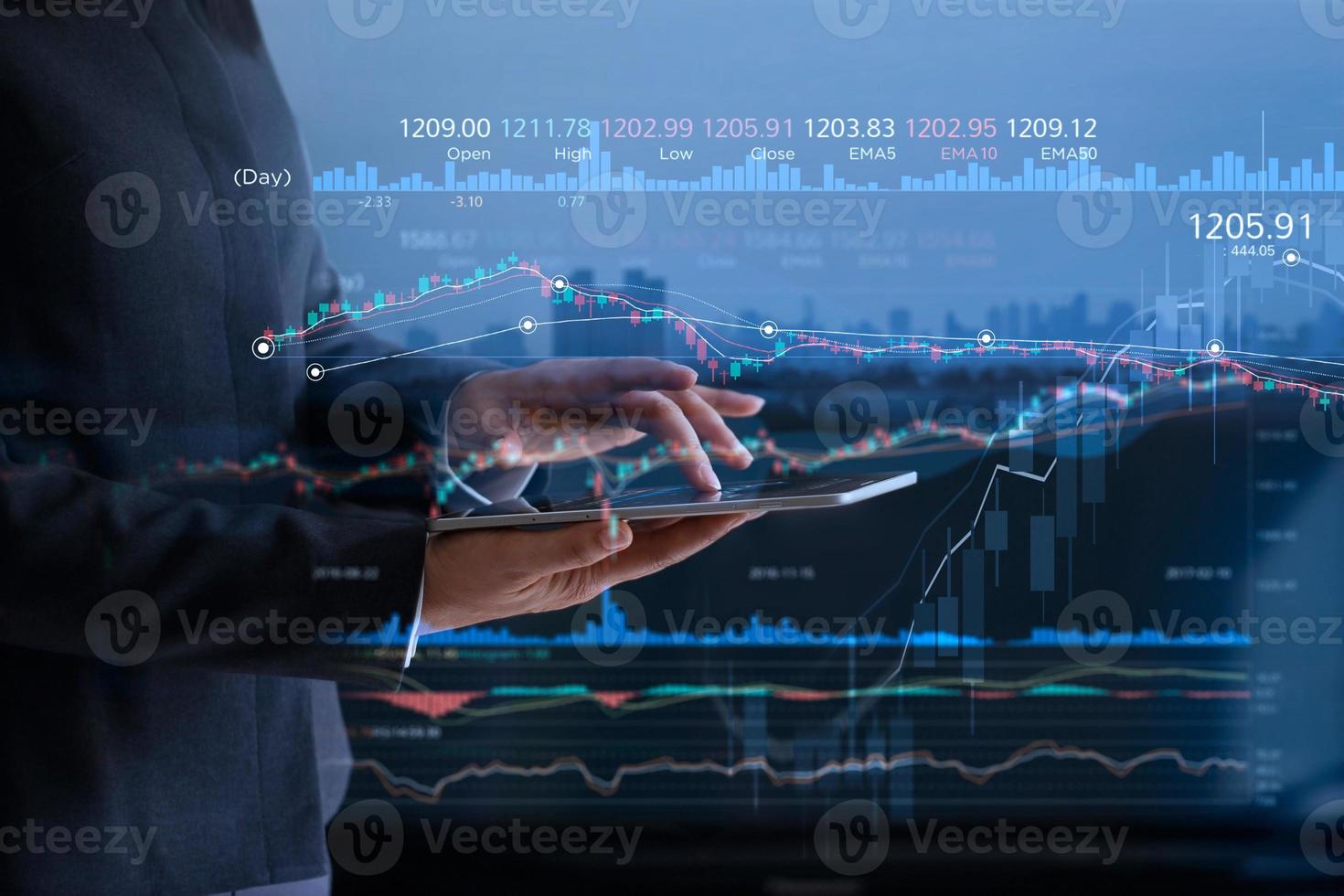Business people checking stock market on tablet and analysing financial data on a screen with graph and candlestick chart on LED monitor virtual on the city background photo