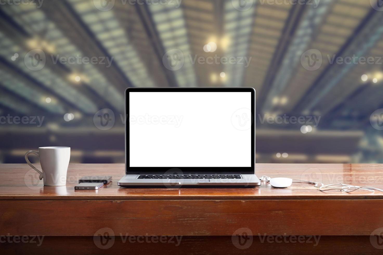 Laptop with blank white screen on table in factory background photo