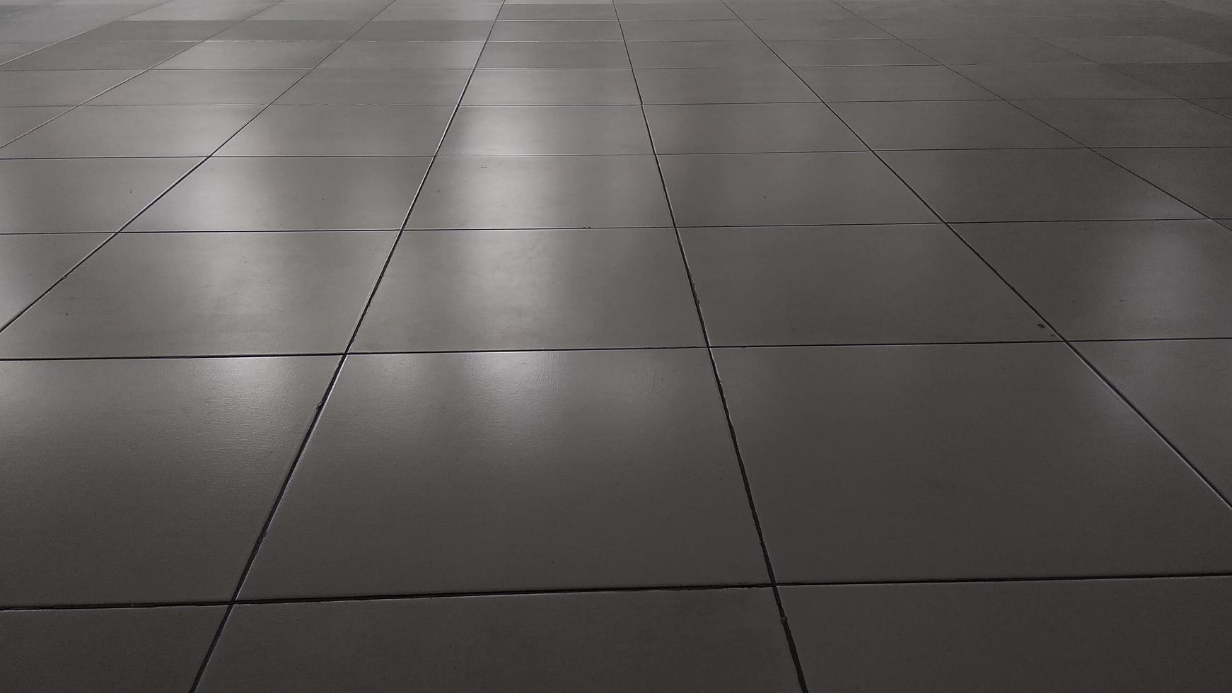 White ceramic tile floor in dim light room with soft light and shadow from outside of the building photo