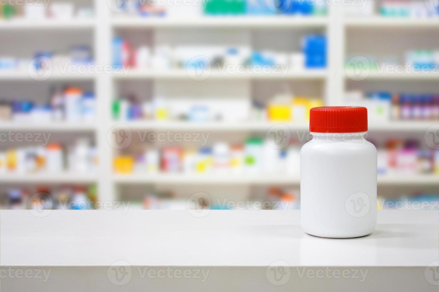 frasco de medicina blanco en blanco en el mostrador con estantes borrosos de medicamento en la farmacia foto