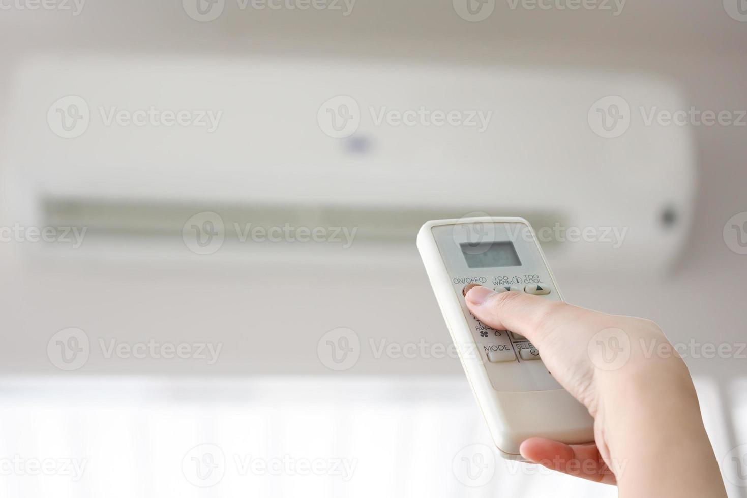 Hand with remote control directed on air conditioner photo