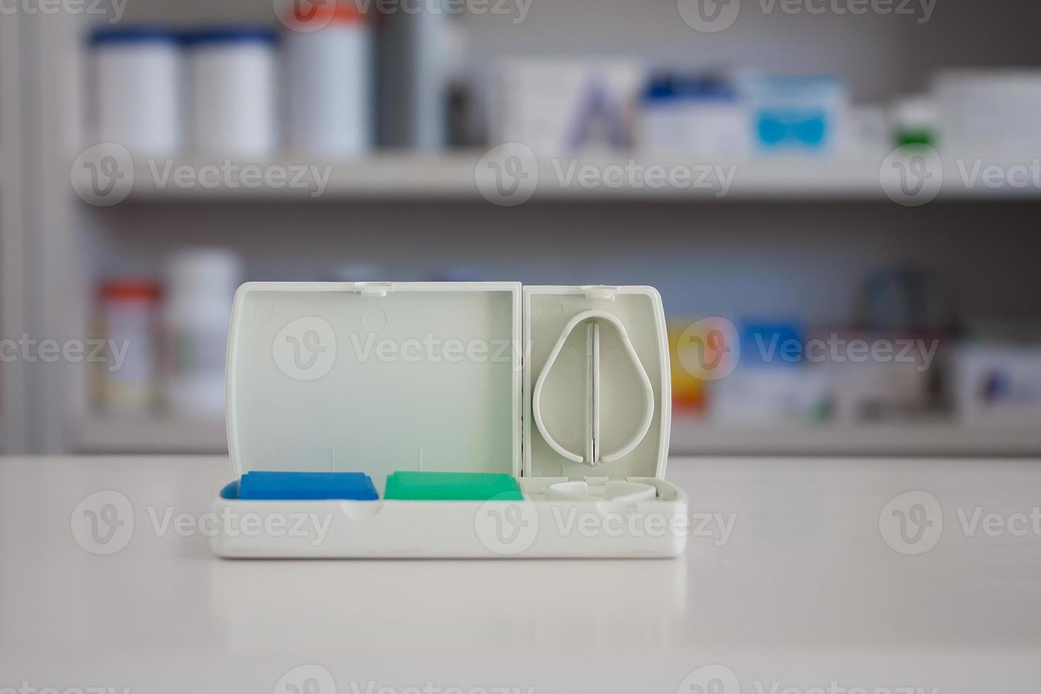cortador de tabletas con estantes borrosos de medicamentos en el fondo de la farmacia foto