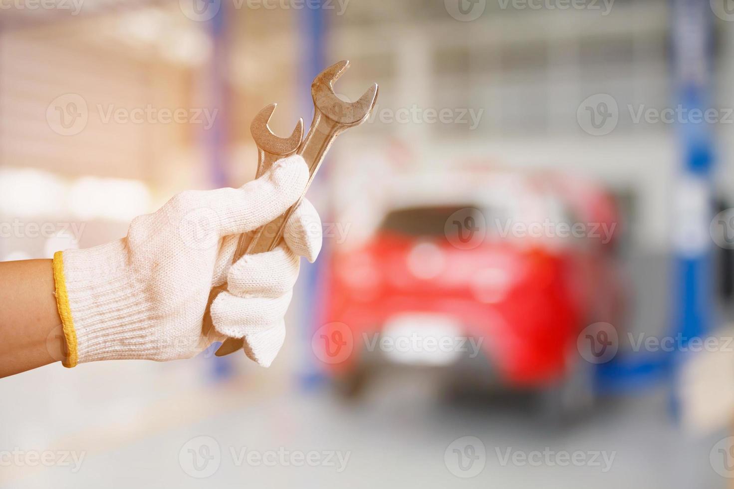 Car mechanic holding wrench at the car repair garage photo