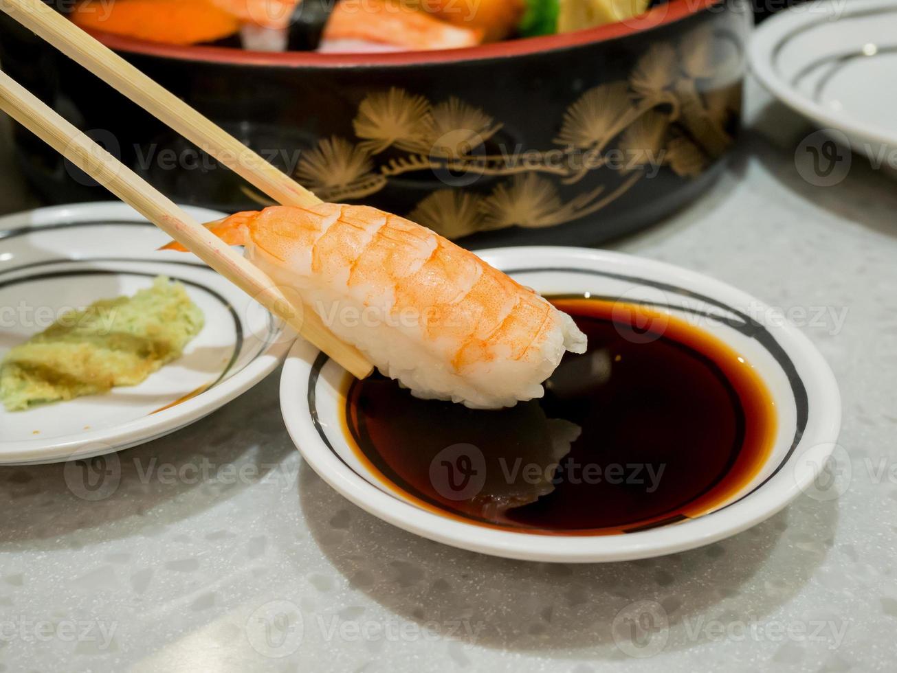 prawn sushi in chopsticks dipping with soy sauce photo