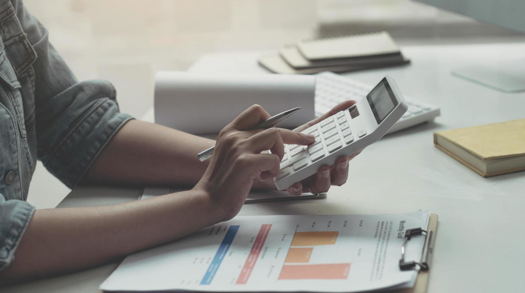 Close up woman working with calculator, business document and laptop computer notebook photo