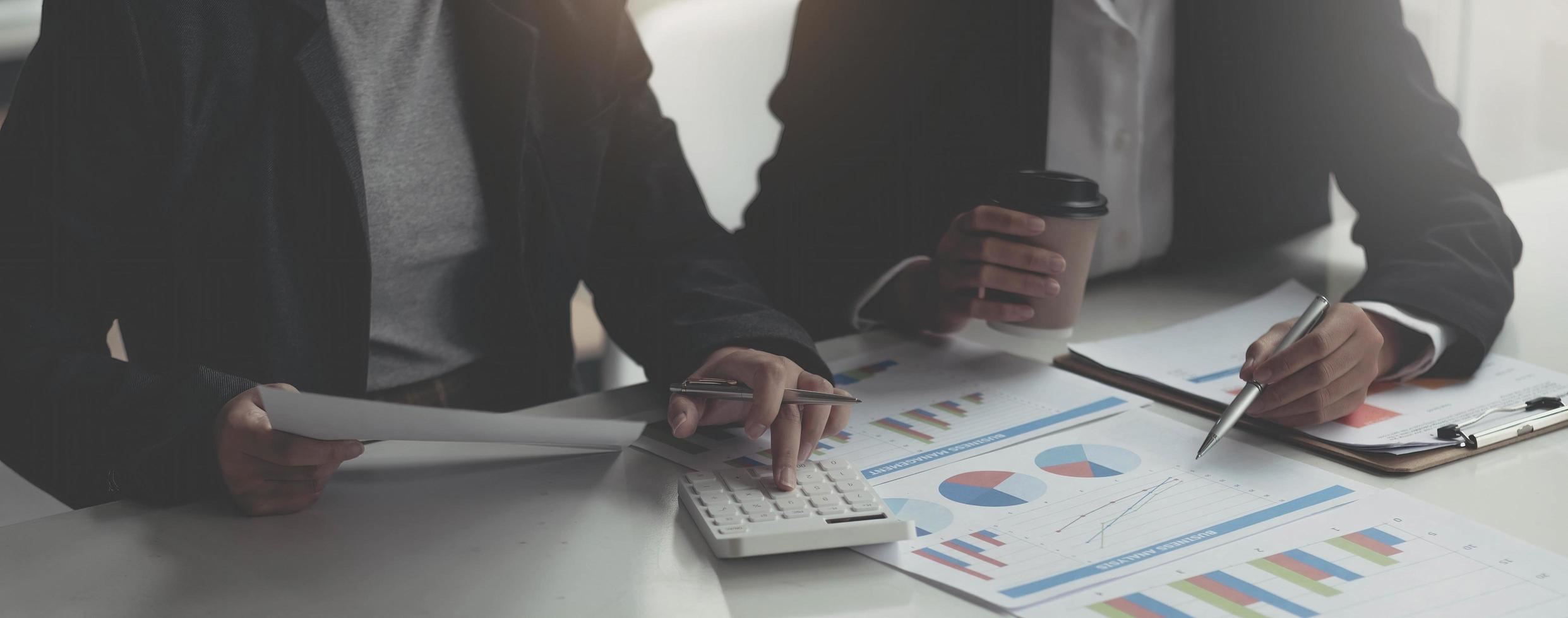 Business analyst pointing to earnings charts and graphs. Analysts are calculating the numbers with a calculator for good future earnings. photo