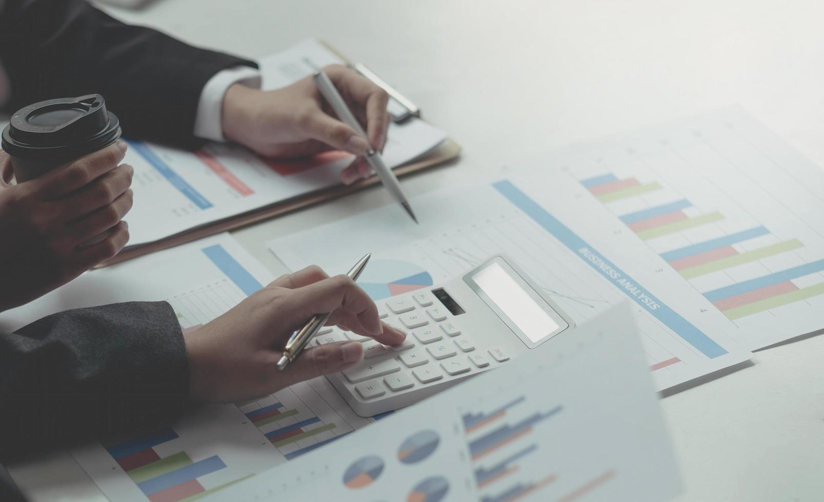 Close up business analyst pointing to earnings charts and graphs. Analysts are calculating the numbers with a calculator for good future earnings. photo