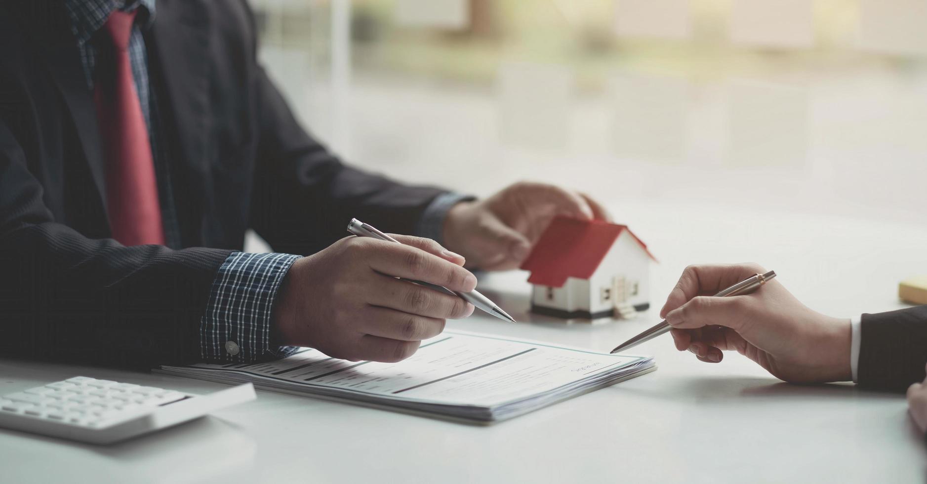 modelo de casa con el agente y el cliente discutiendo el contrato para comprar, obtener un seguro o un préstamo de bienes raíces o propiedades. foto