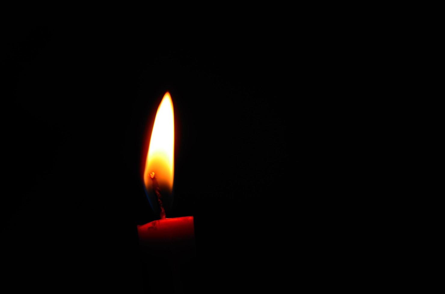 red candle on a bldetail view from a red burning candle in the black night during war photo