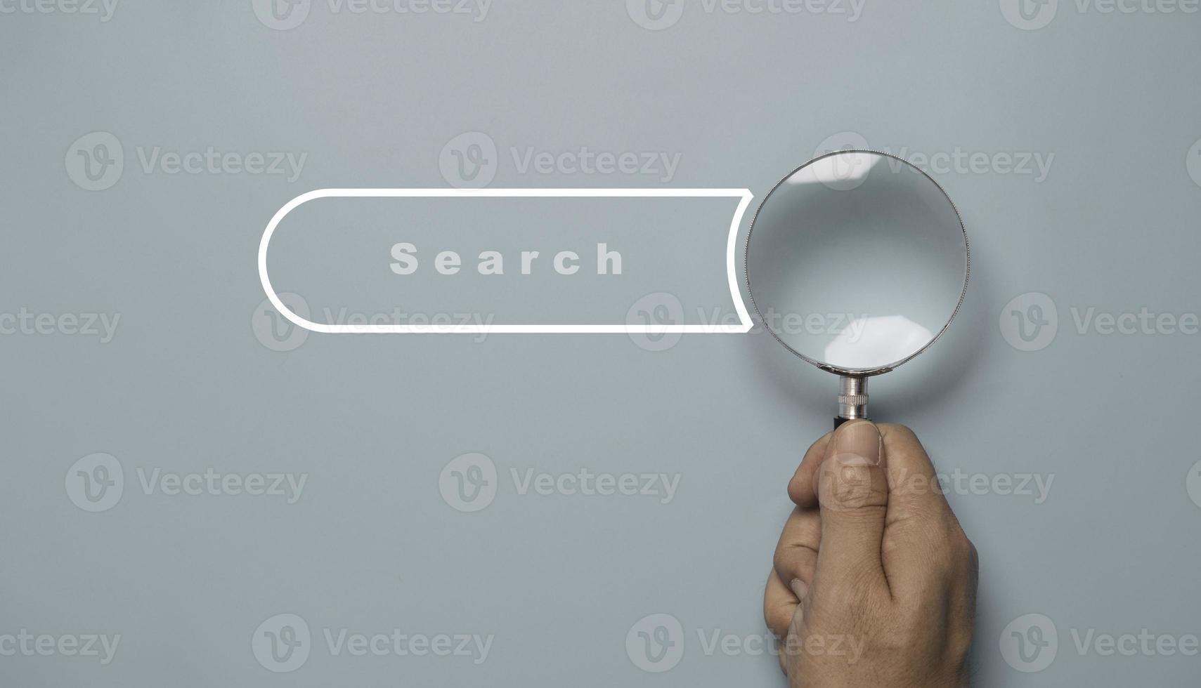 Hand holding magnifier glass with search bar icon for SEO or Search Engine Optimisation wording concept. photo
