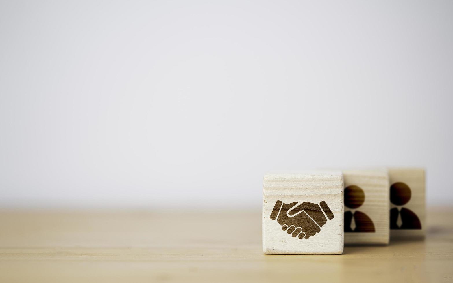 Hand shaking which print screen on wooden cube block  in front of human icon for business deal and agreement concept. photo