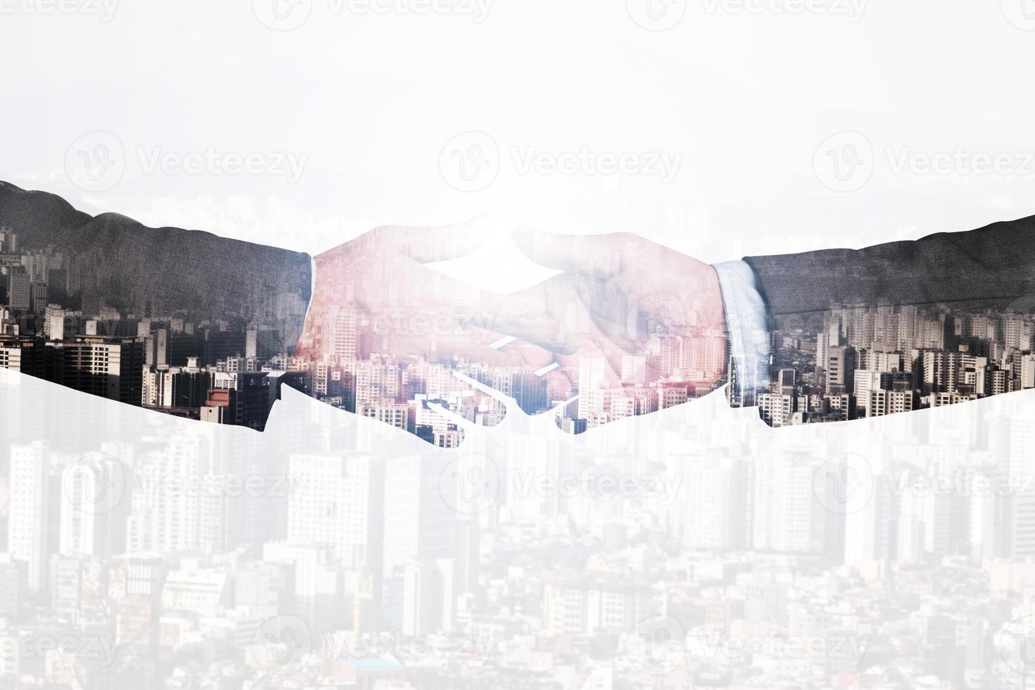 Double exposure of two businessmen hand shaking with city scape concept. photo