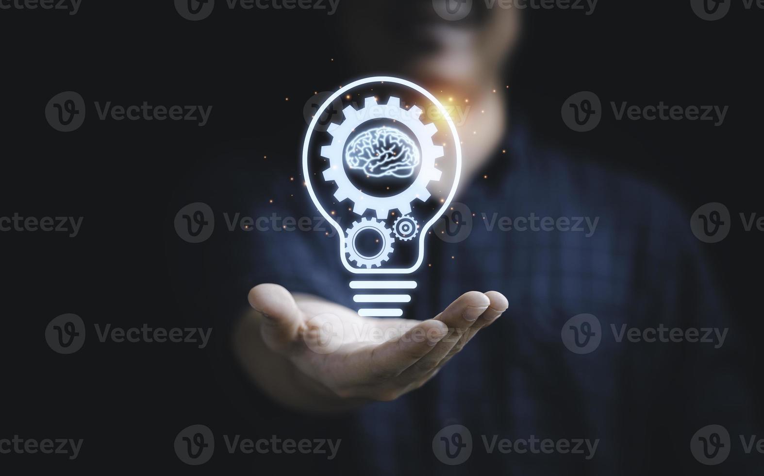 Businessman holding virtual lightbulb with mechanical gear and brain for creative thinking idea and innovation concept. photo