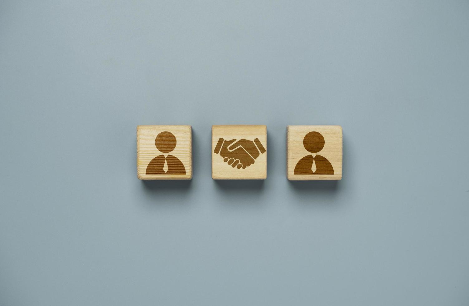 Drawing of hand shaking which print screen on wooden cube block  in front of human icon for business deal and agreement concept. photo