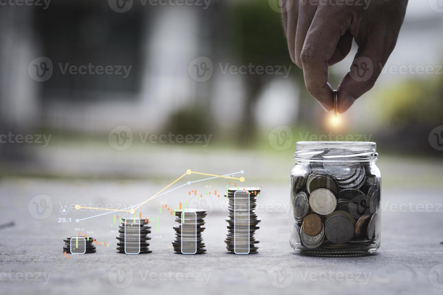 Hand putting coin to saving jar with increasing coins stacking and graph for growth profit from interest concept. photo